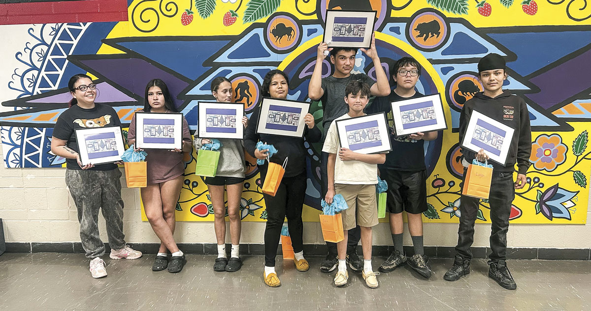 Group of students in front on Indigenous art wall holding framed Indigenous Art