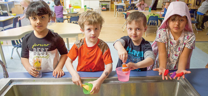 Happy Kindergarten students playing with water