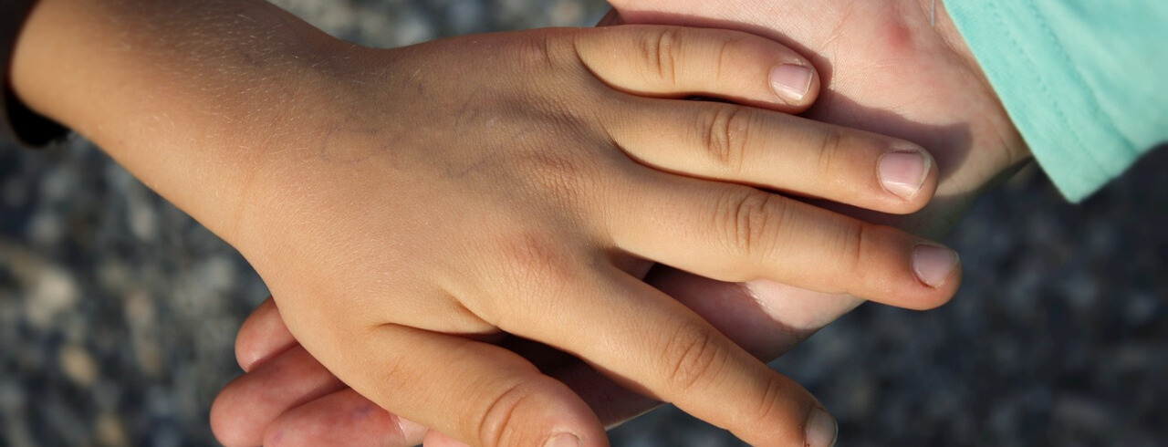 a kid hand over an adult hand