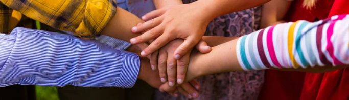 Group of kids with 'hands in' team gesture